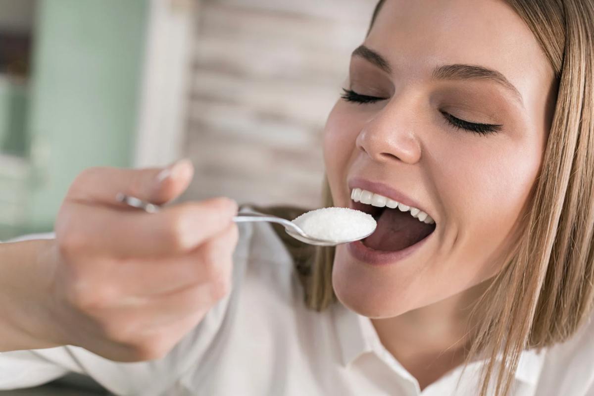 Donna che sta per mettere in bocca un cucchiaino di zucchero