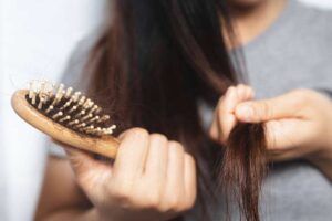 Donna con spazzola piena di capelli in mano