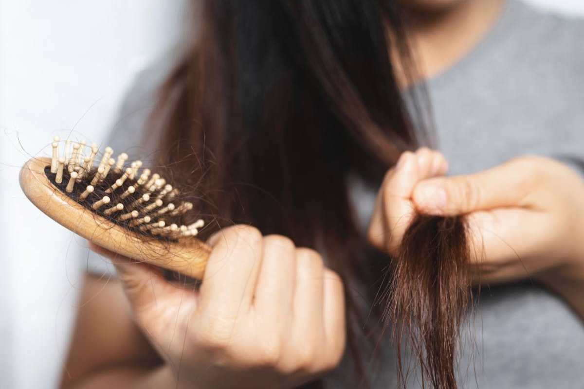 Donna con spazzola piena di capelli in mano