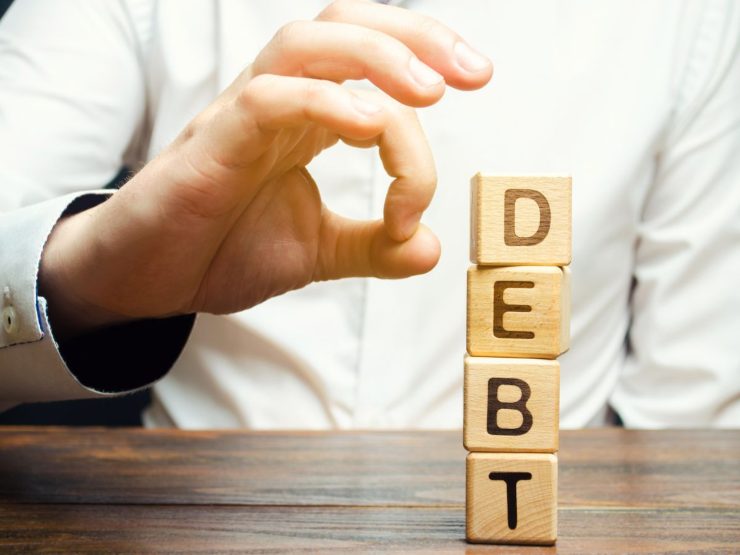 Mano che cerca di far cadere dei dati con scritto Debt