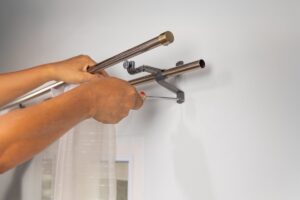 Uomo che smonta i bastoni per le tende di casa