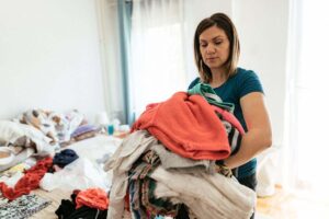 donna con tanti vestiti da riordinare