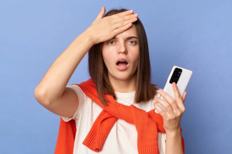 donna con il cellulare in mano e l'altra mano sulla fronte con espressione stupita