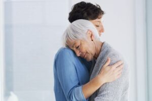 donna anziana abbracciata da assistente sanitaria