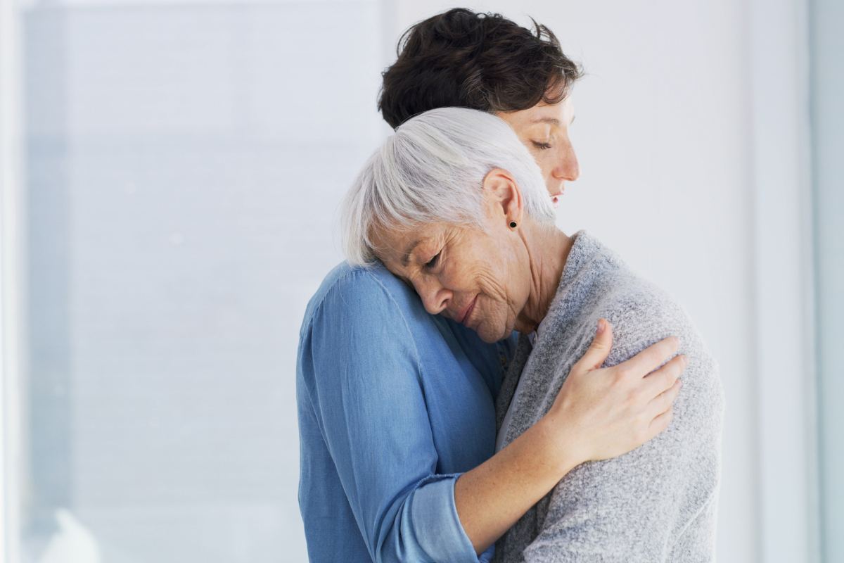 donna anziana abbracciata da assistente sanitaria