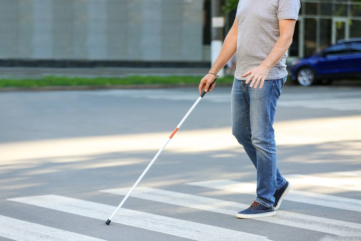 non vedente con bastone attraversa la strada