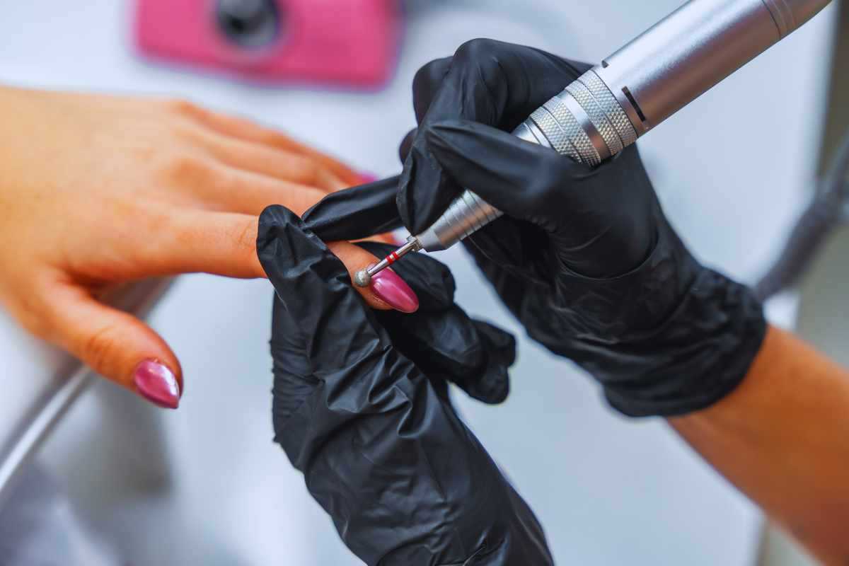 Mani di un'estetista che fanno la unghie ad una cliente